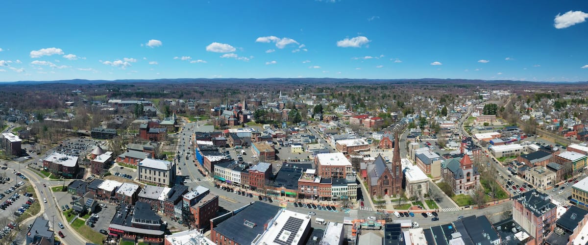A panoramic view of a town with a mix of historic and modern buildings, a prominent church, and a clear blue sky.