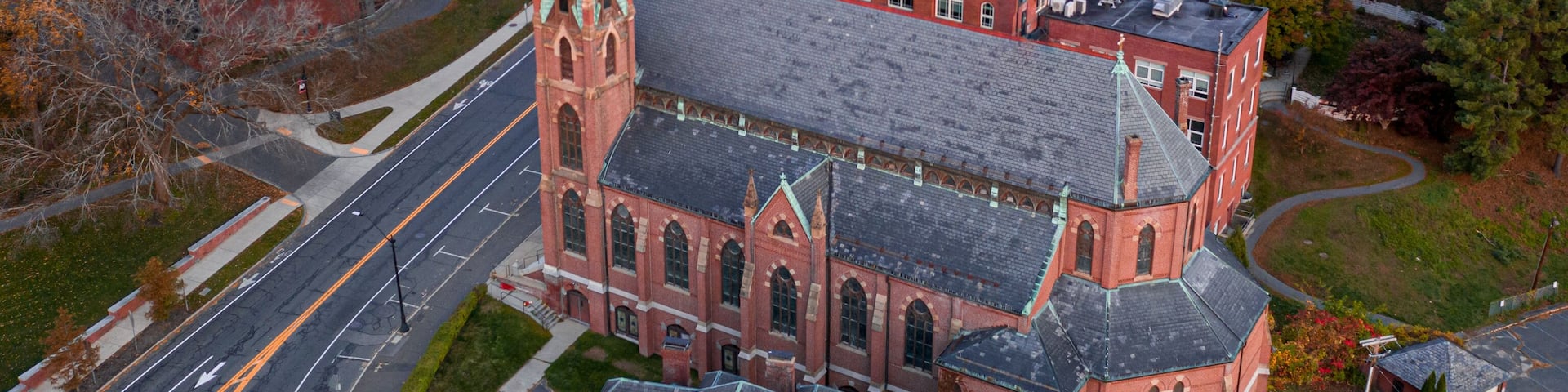 A town with a prominent church, a large industrial building, and autumn-colored trees.
