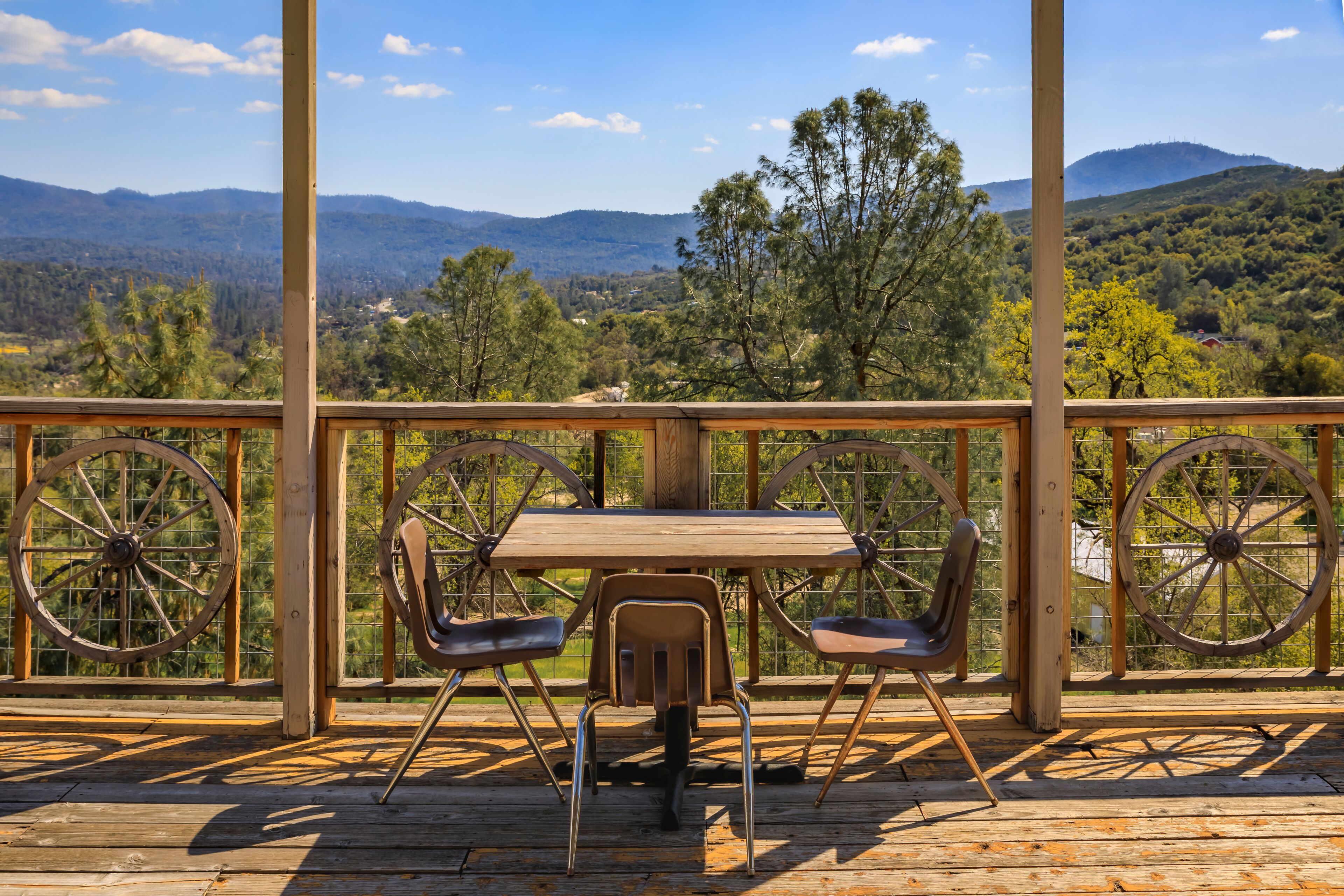 A wooden deck with a table and chairs overlooking a mountainous landscape.