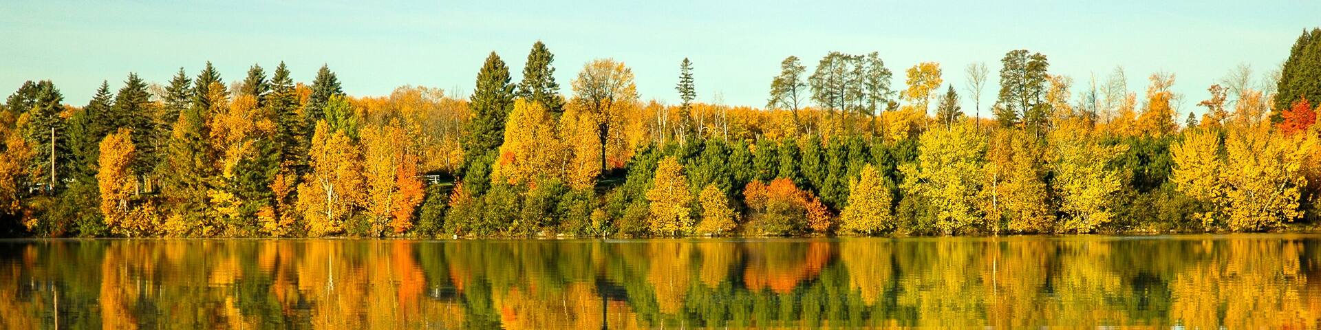 A calm lake reflecting autumn trees.