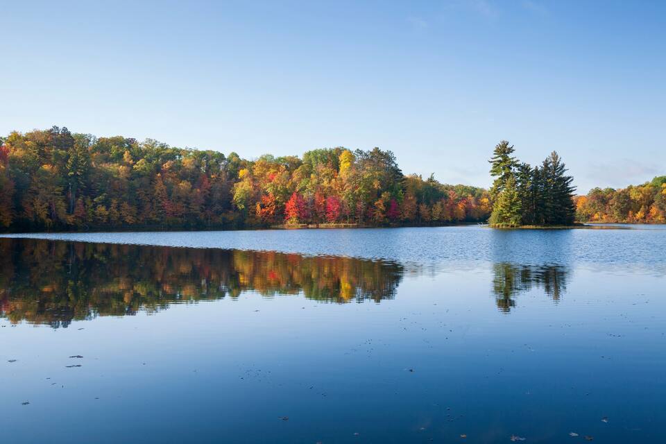 A calm lake reflecting colorful autumn trees.