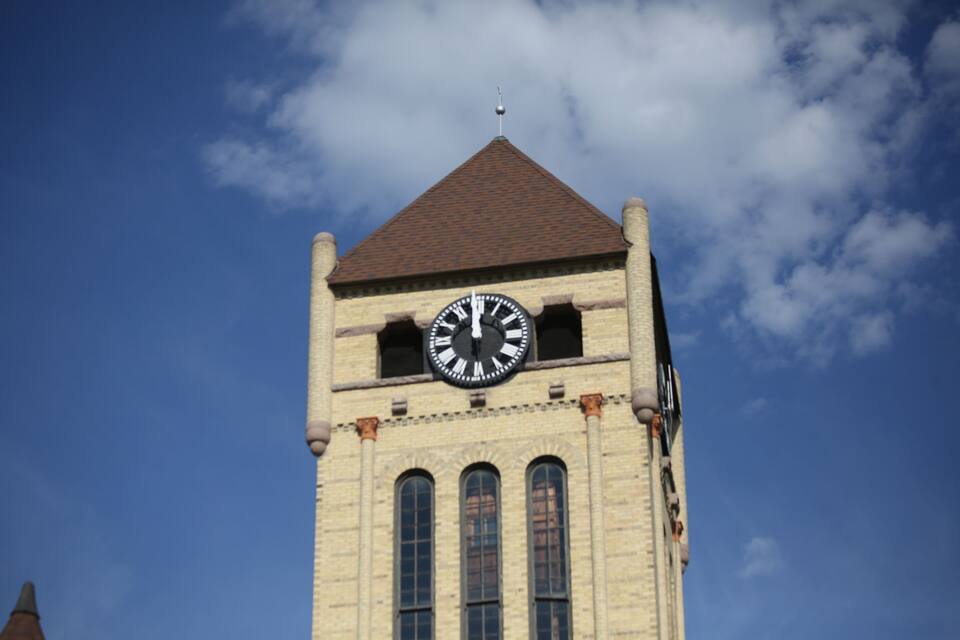A clock tower with a brown roof and a weather vane.