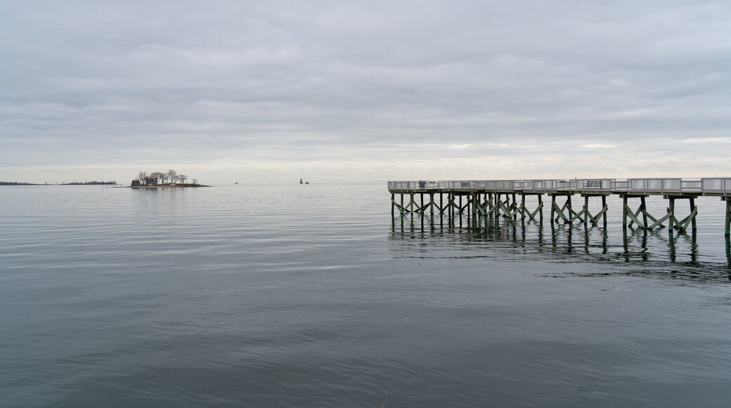 A view of the long pier and the Long Island Sound at Calf Pasture Beach in Norwalk, Connecticut USA on a cold and grey December day. The flat light lends a dreamy feel to the scene.