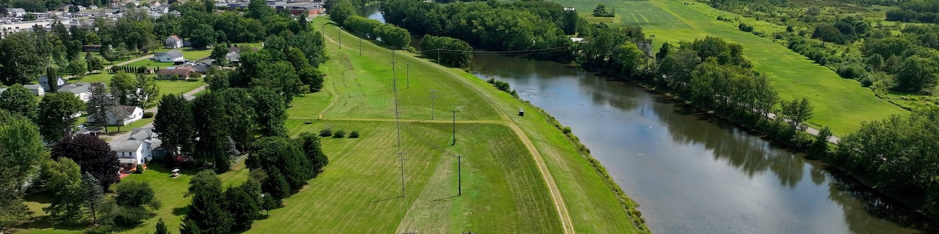 Peaceful countryside landscape in Olean, NY with river, hills, green pastures under blue sky and clouds