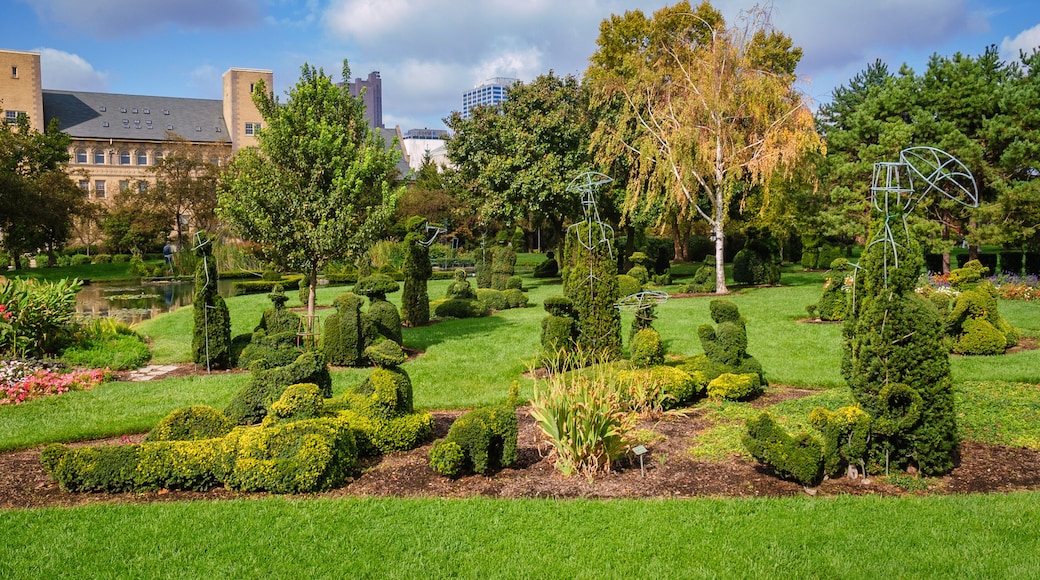 A well-manicured garden with topiary, a pond, and a variety of trees and shrubs.