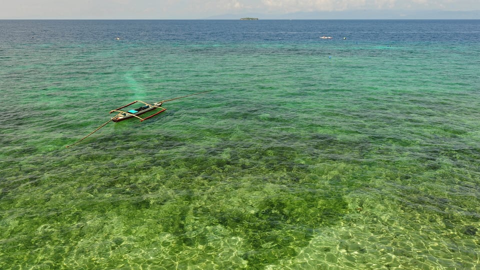 A boat on clear turquoise water with a distant island.