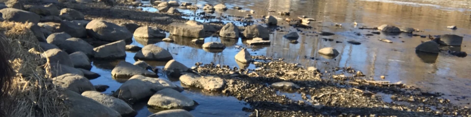 A river with rocks and a waterfall in the background.
