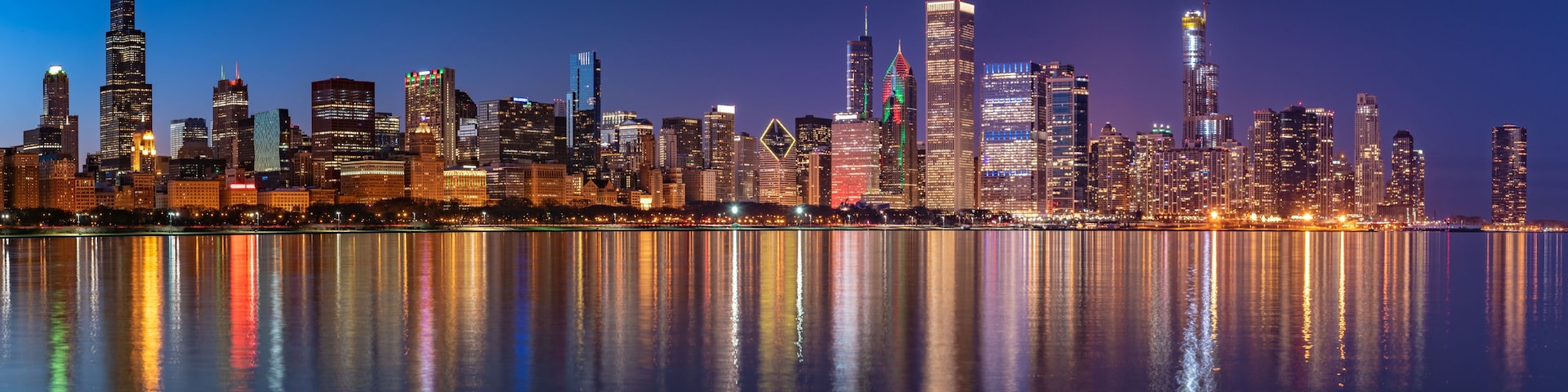 A city skyline at night with reflections in the water.