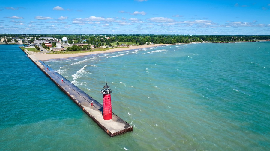 Aerial View of Red Lighthouse on Pier with Coastal Town in Background