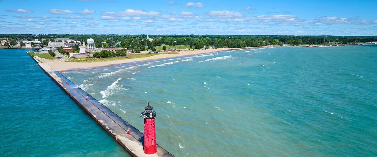 Aerial View of Red Lighthouse on Pier with Coastal Town in Background