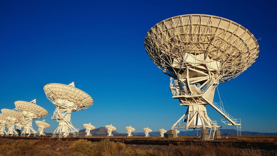 A series of large satellite dishes in a desert landscape.