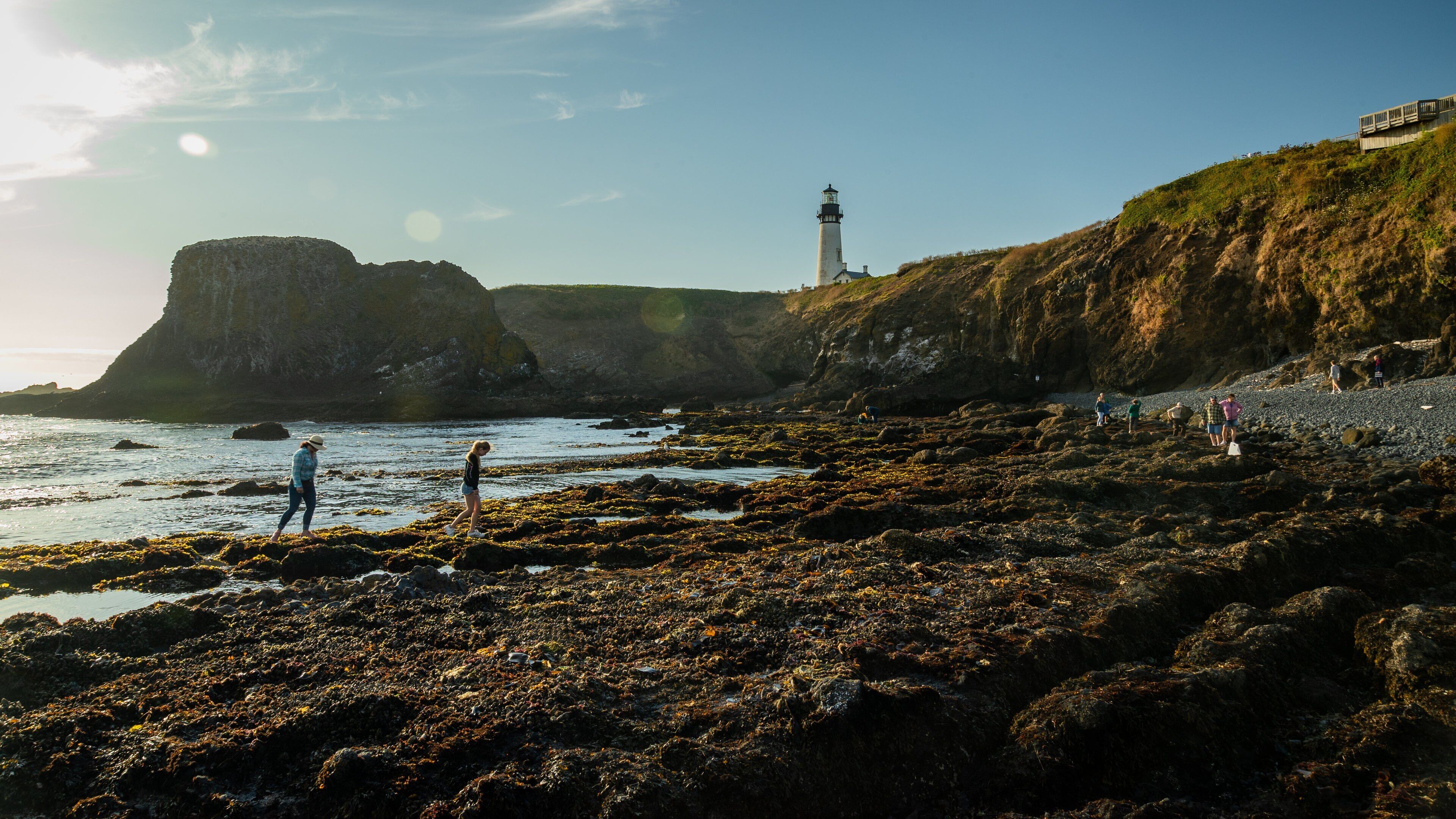 A rocky beach with a lighthouse and a large cliff.