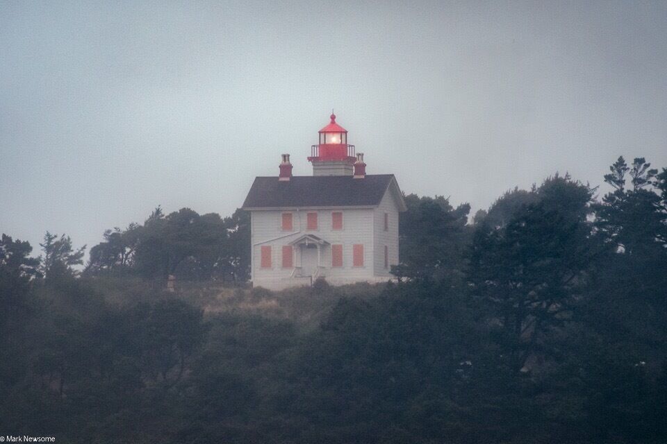Yaquina Bay lighthouse as seen from the beach on a foggy day.