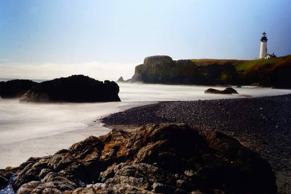 A rocky shoreline with a lighthouse in the background.
