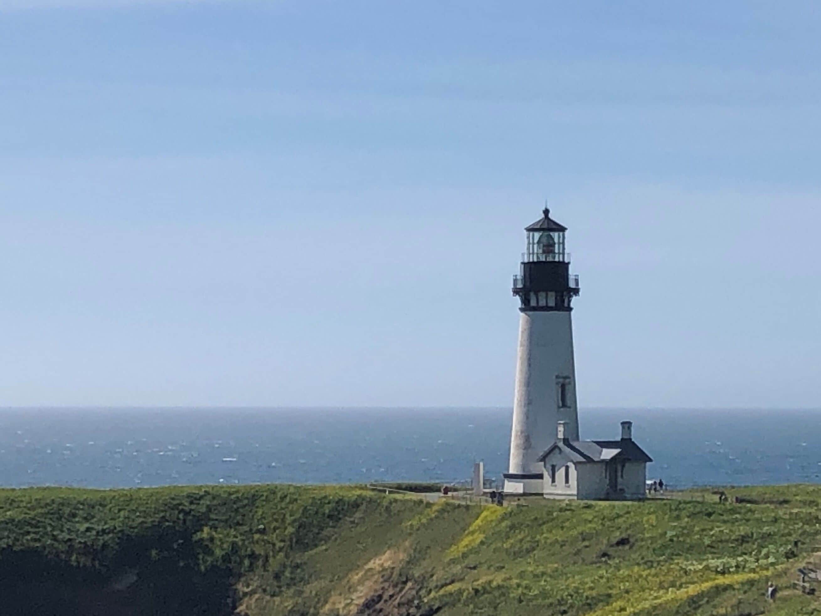 Un faro en un acantilado cubierto de hierba con vista al mar.