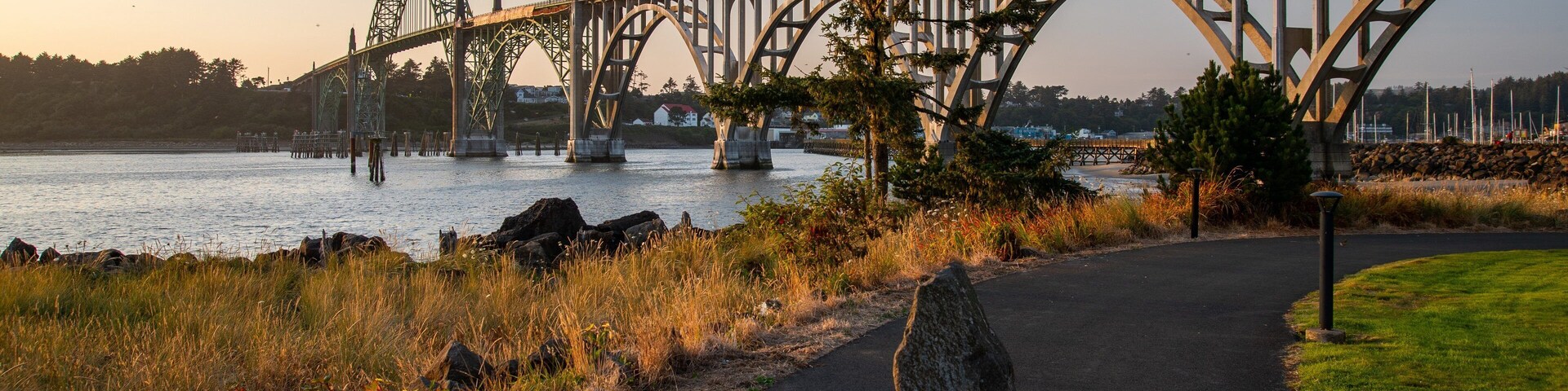 Un puente de acero sobre un río con una senda peatonal a su lado.