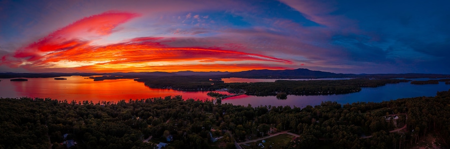 Un atardecer sobre un lago rodeado de colinas boscosas.
