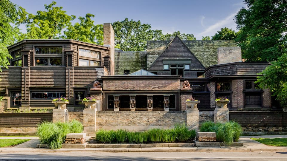 A large, modern house with a stone facade, large windows, and a prominent chimney.