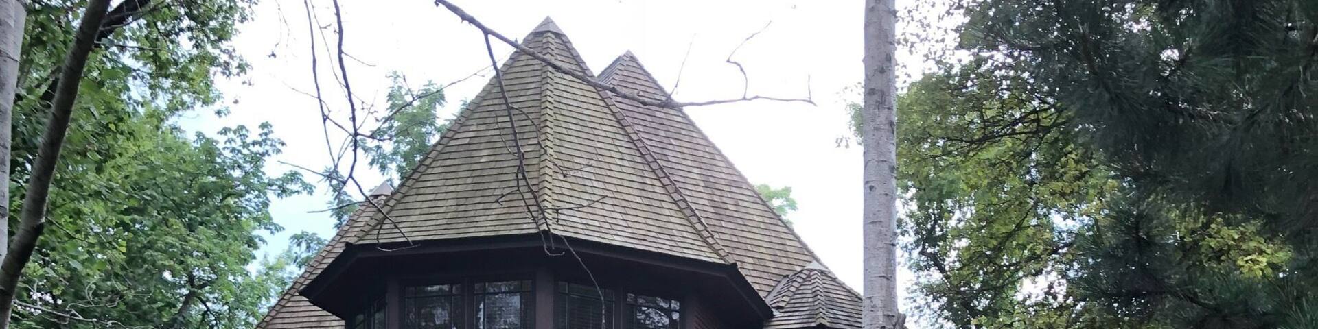 A two-story house with a steeply pitched roof and a brick pathway leading to it.