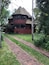 A two-story house with a steeply pitched roof and a brick pathway leading to it.