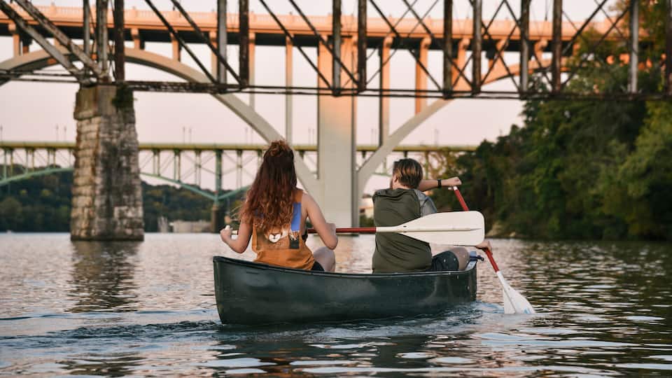 A canoe on a river with a bridge in the background.