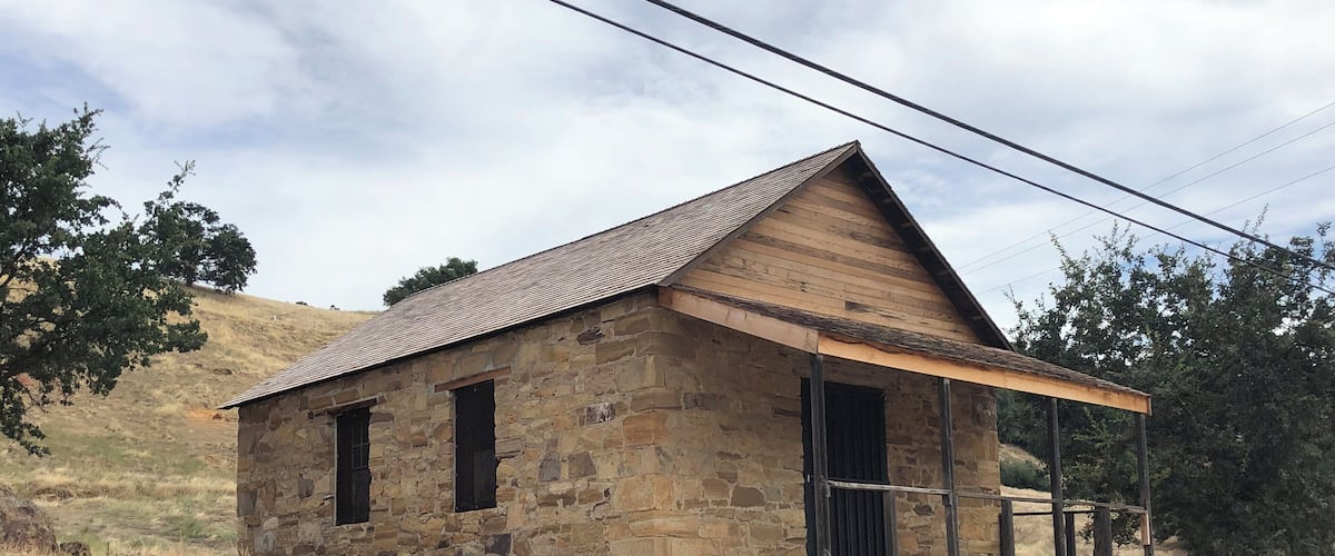 A stone building with a wooden roof and a porch.