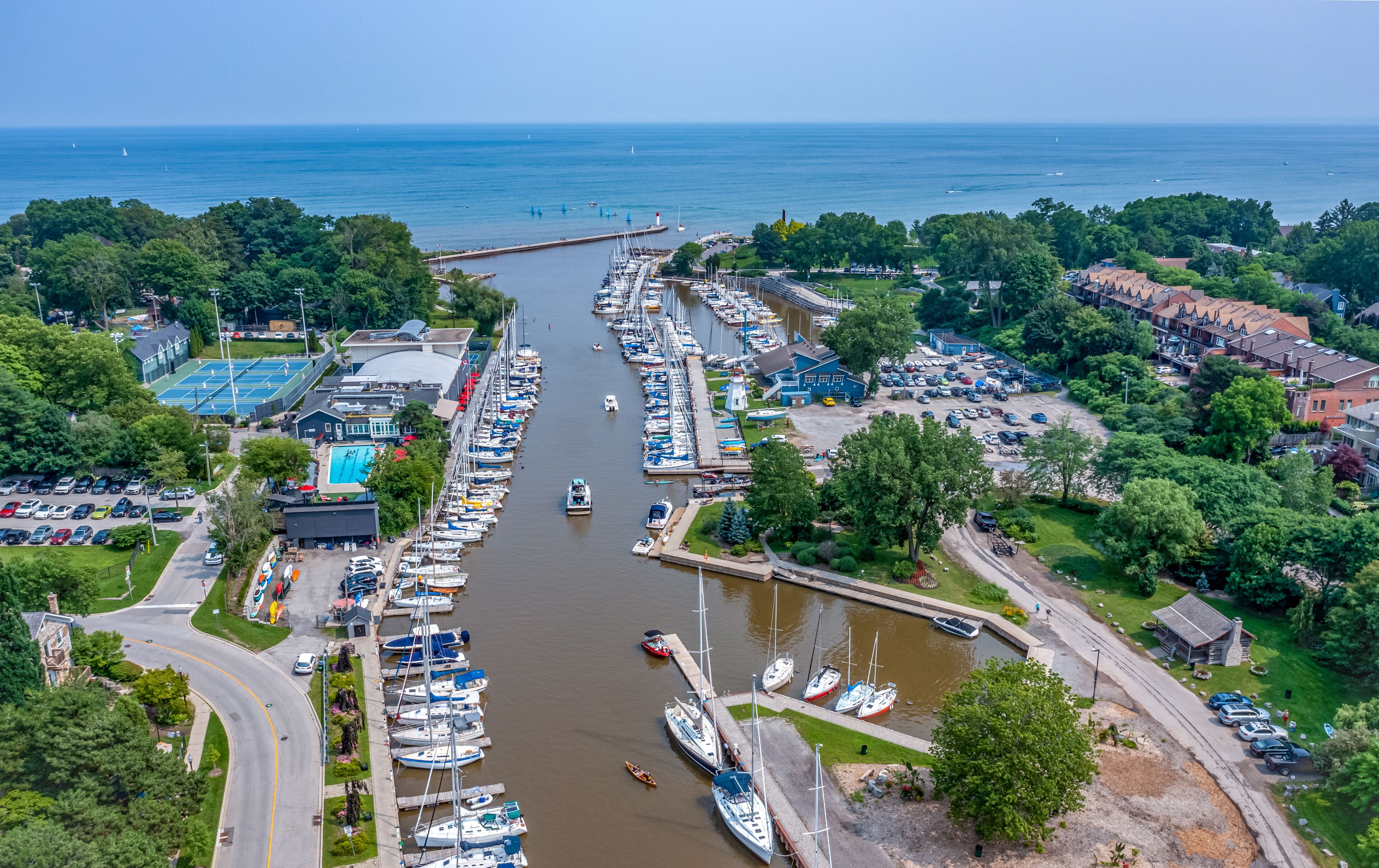 A marina with boats docked along a narrow waterway, surrounded by residential buildings and greenery.