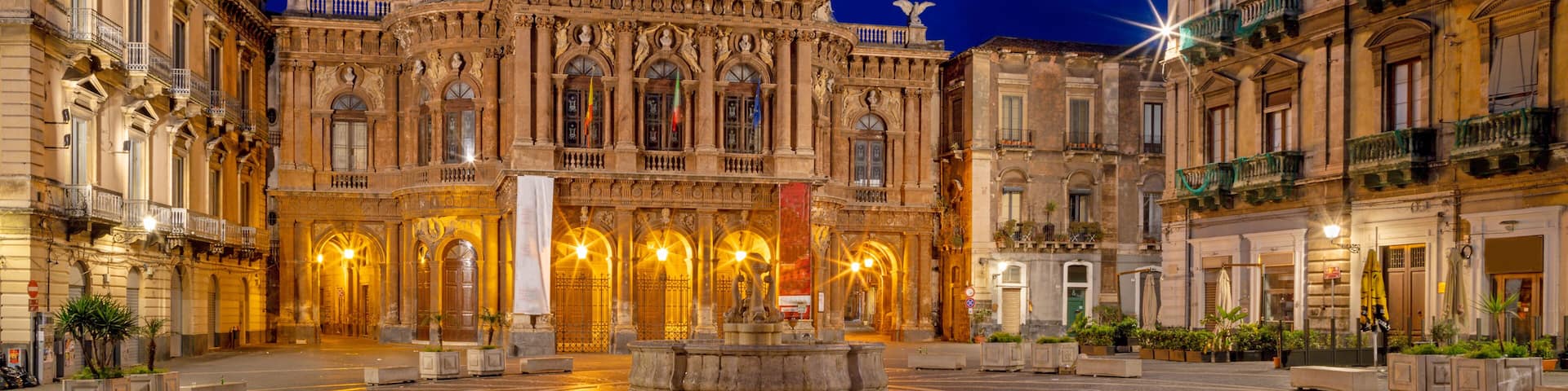 A historic building with ornate architecture, a central fountain, and cobblestone streets.