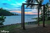 A wooden swing set by a lakeside at sunset.