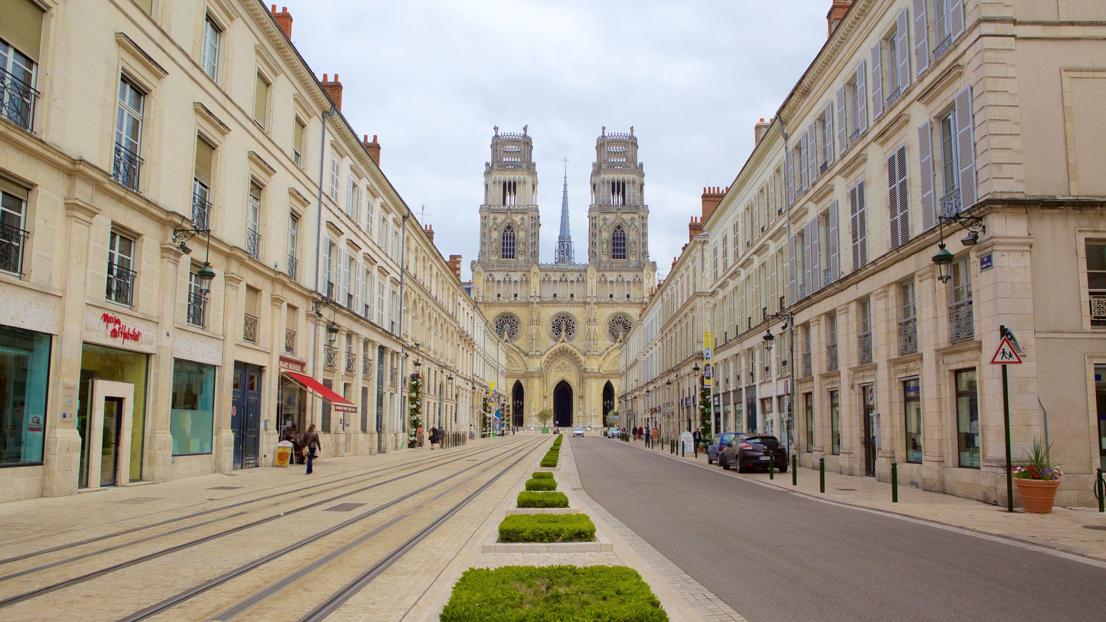 A street leading to a historic cathedral with twin towers and a spire.