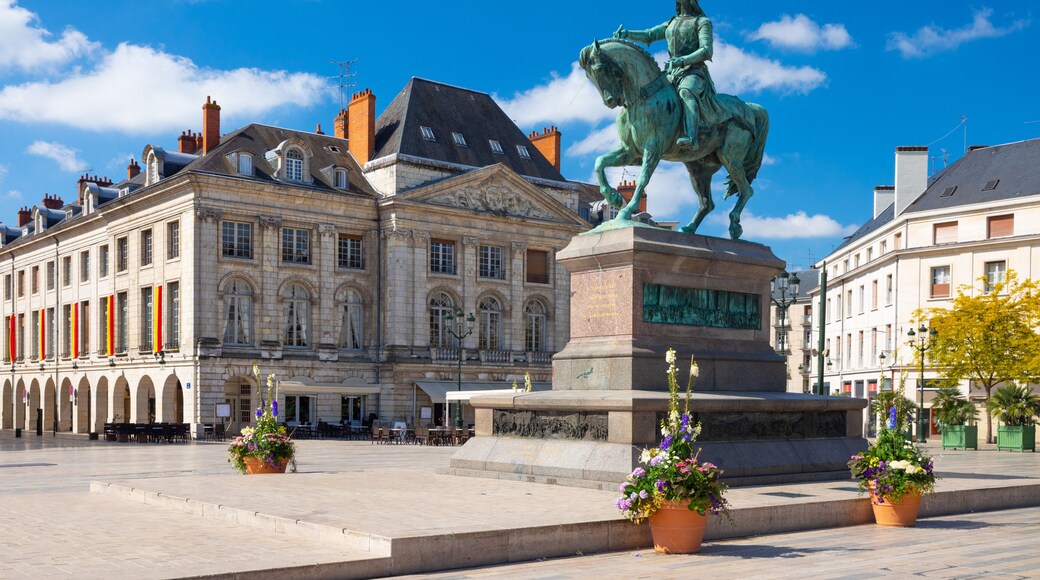 A statue of a man on horseback in front of a historic building with arched windows and a balcony.