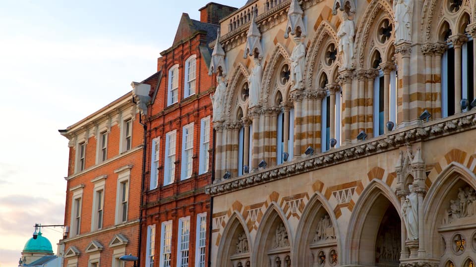 A historic building with red brick and ornate stonework, including statues and arches.