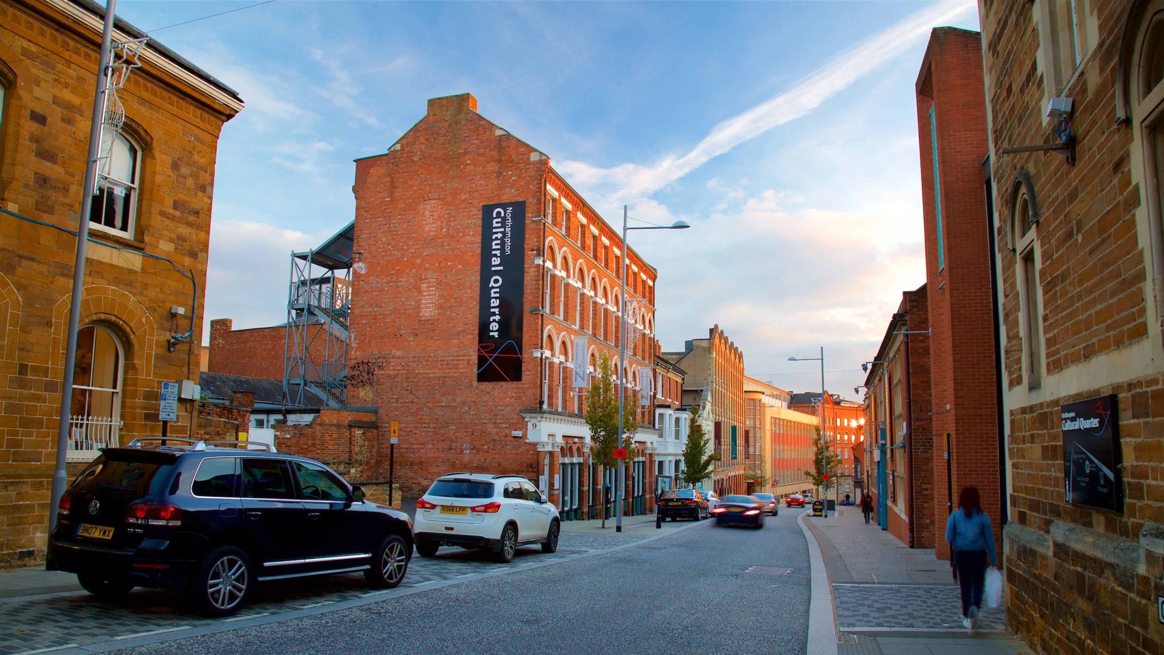 A street lined with historic buildings, including a prominent red brick building with a sign for the National Gallery.