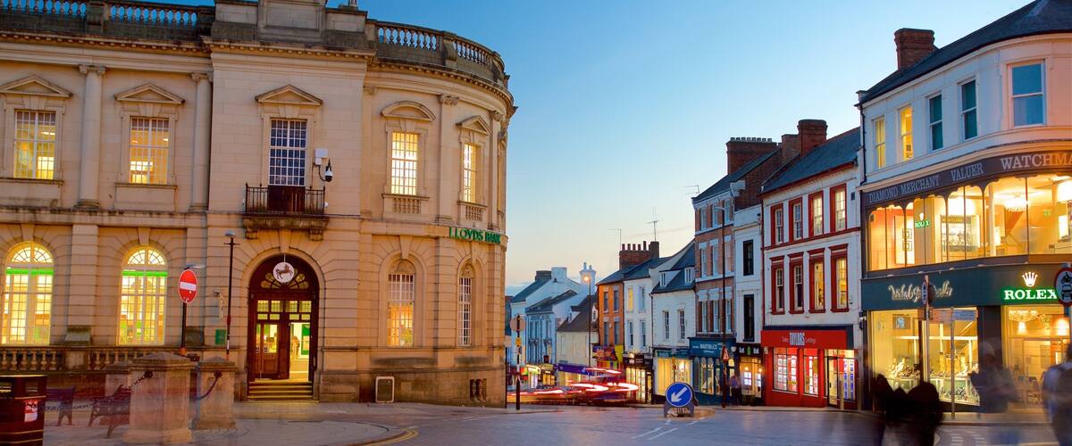 A historic building with a Lloyds Bank sign, a Rolex store, and a street with cobblestones.