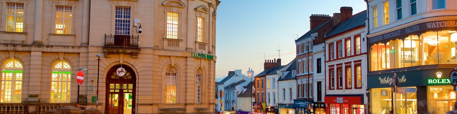 A historic building with a Lloyds Bank sign, a Rolex store, and a street with cobblestones.