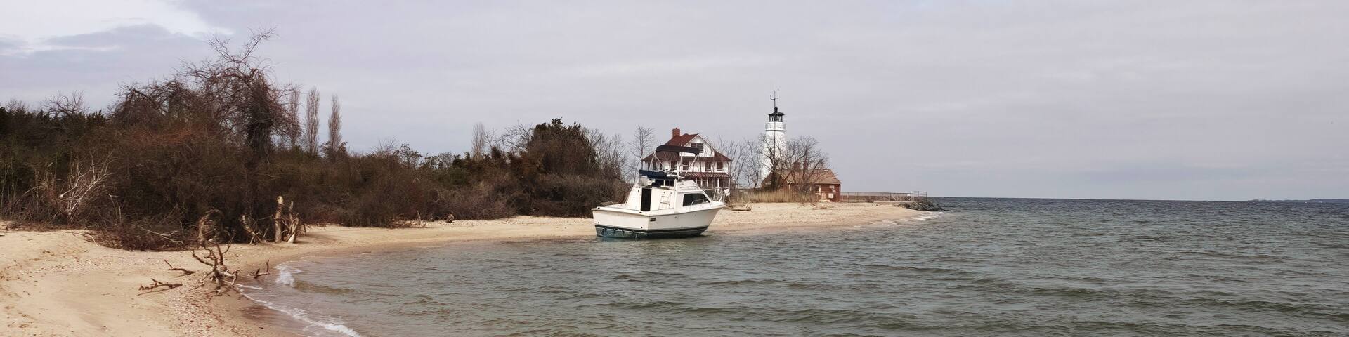 A sandy beach with a boat near a lighthouse.