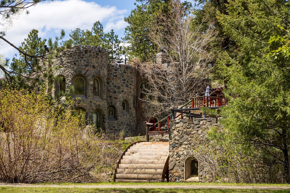 A stone building with arched windows and a staircase leading up to a red door.