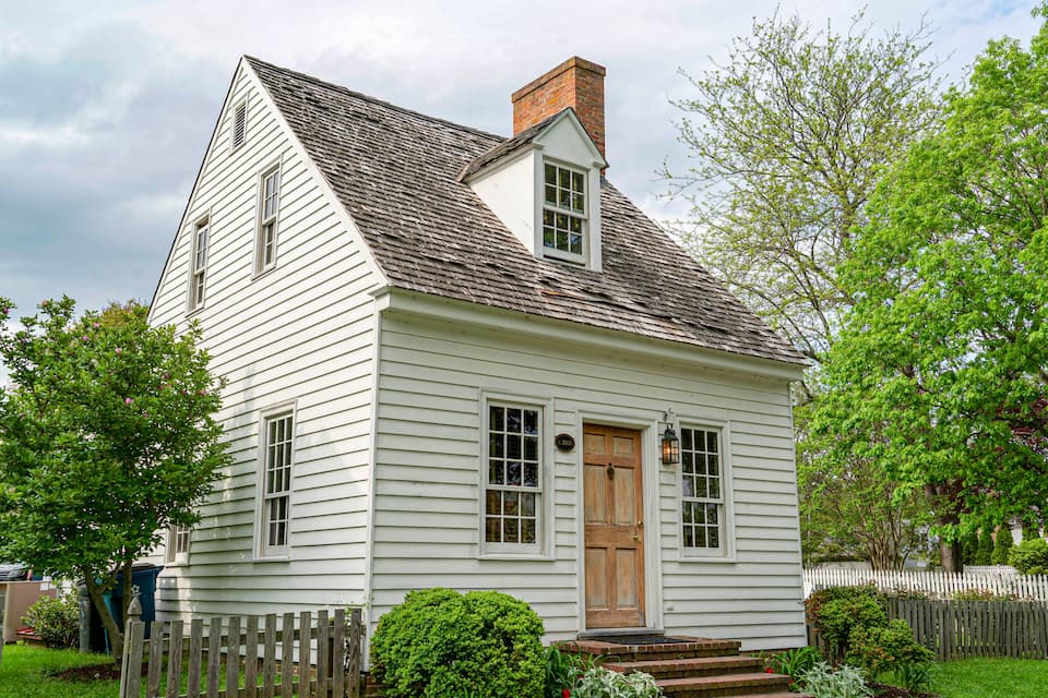 Une maison en bois blanche, avec une porte marron et une petite fenêtre.