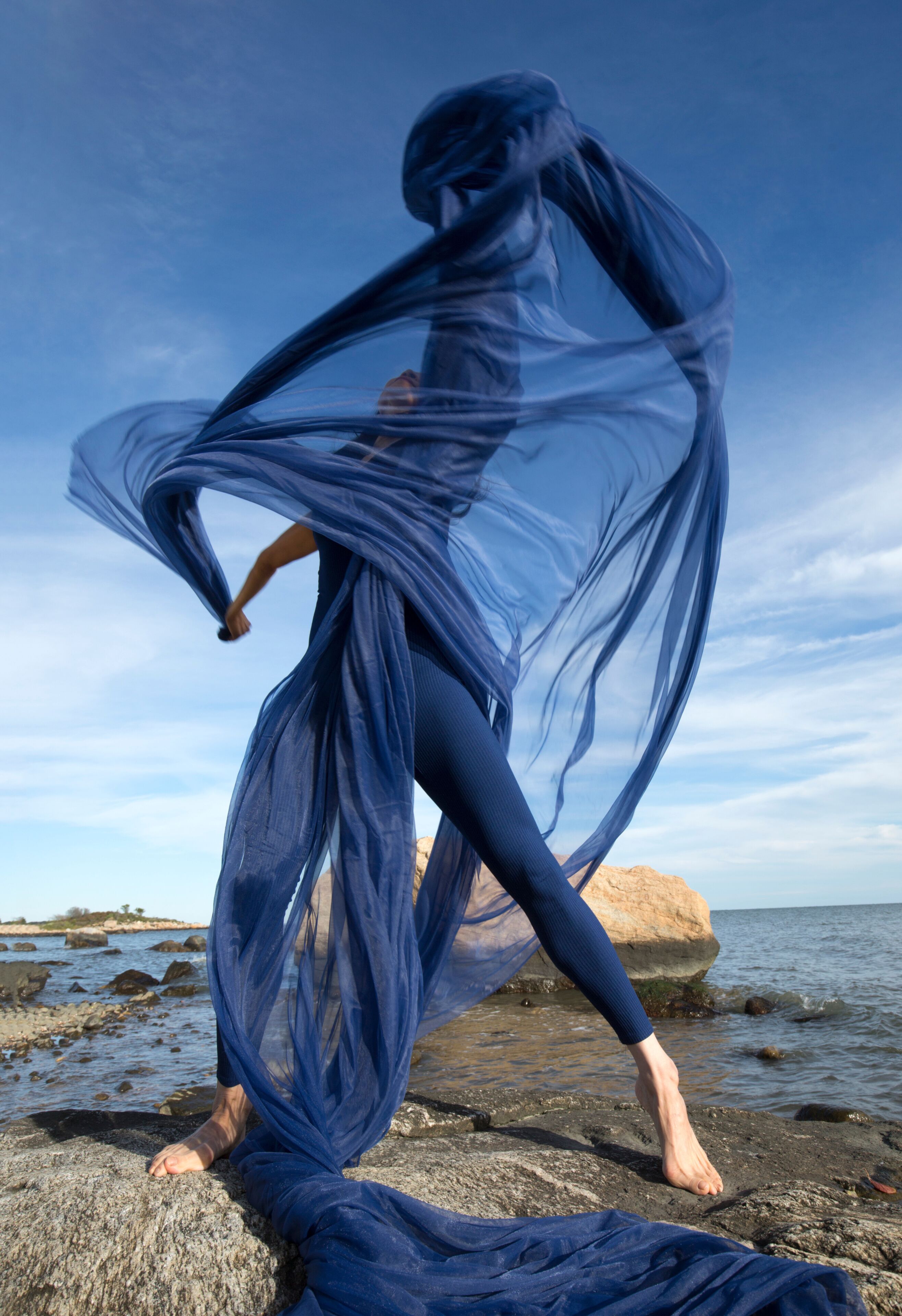 Woman dancing with blue fabric on the beach in Connecticut.