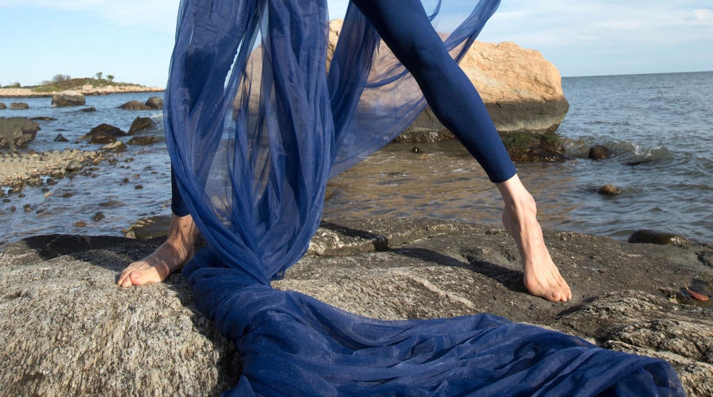 Woman dancing with blue fabric on the beach in Connecticut.