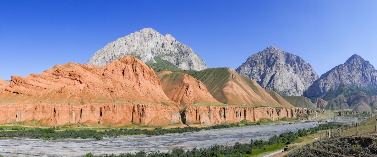 A river flowing through a mountainous landscape with prominent red and green rock formations.