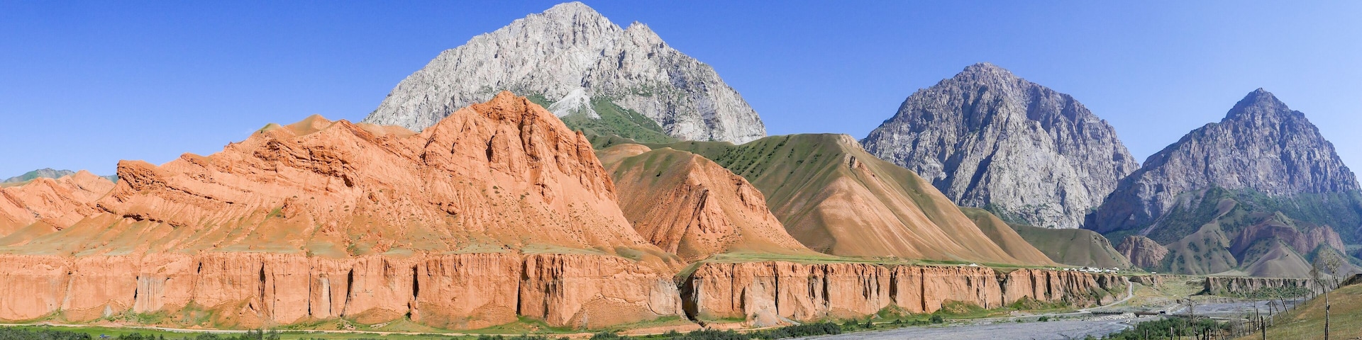 A river flowing through a mountainous landscape with prominent red and green rock formations.