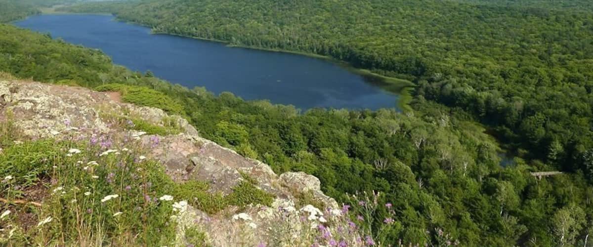 A lake surrounded by dense forest and rolling hills.