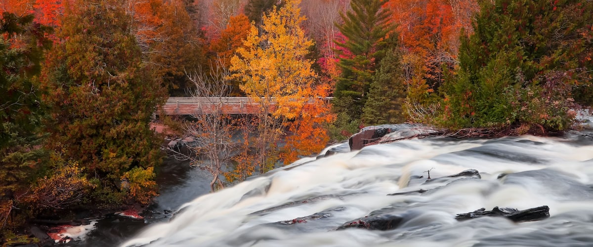 A waterfall surrounded by autumn-colored trees.