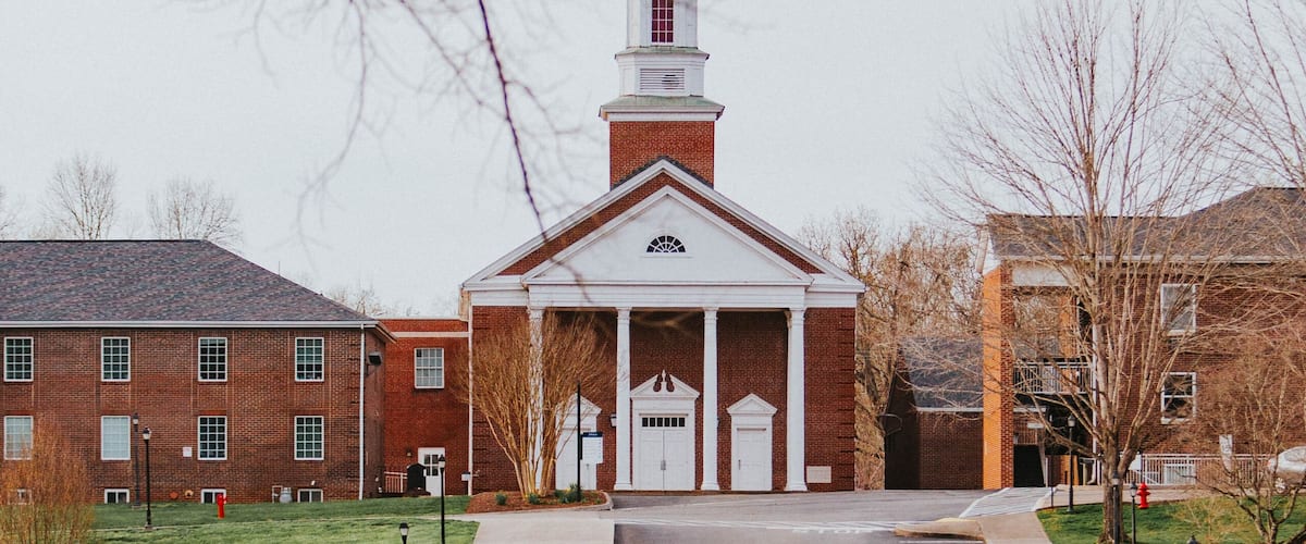 A church with a tall steeple and a brick building.