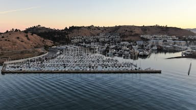 A marina with numerous boats docked, surrounded by hills and residential buildings.