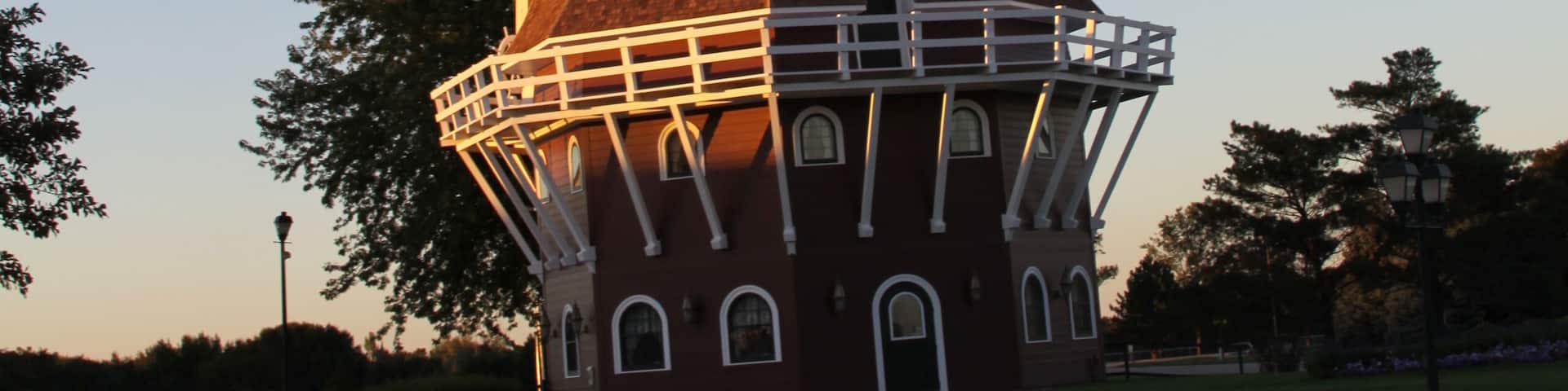 A windmill with a red roof and white lattice structure.