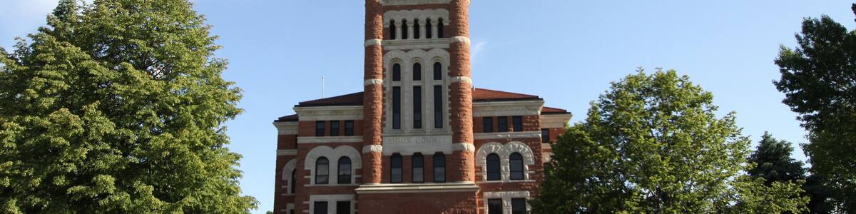 A large brick building with a clock tower and a statue on top.