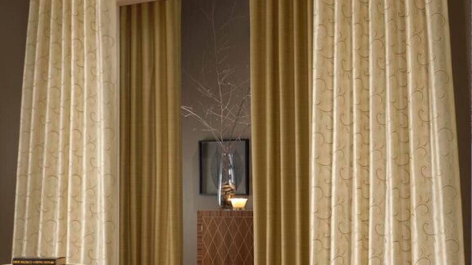 A room with beige curtains, a patterned rug, and a wooden table.