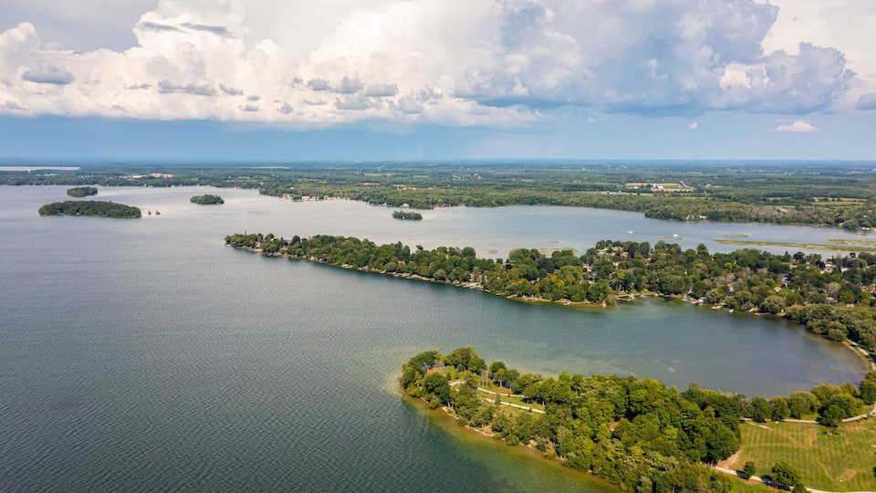 A large lake with several islands, surrounded by dense forests and a clear sky.